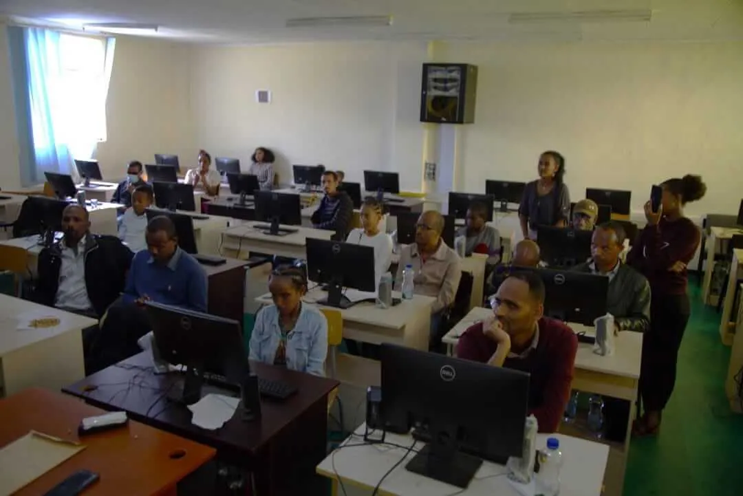 A group of students sitting at computer workstations inside a classroom, focused on their desktop screens during a training session.