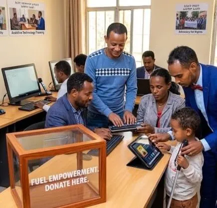 An interactive training setting where individuals work with computer equipment, tablets, and accessible technology devices at a wooden desk.